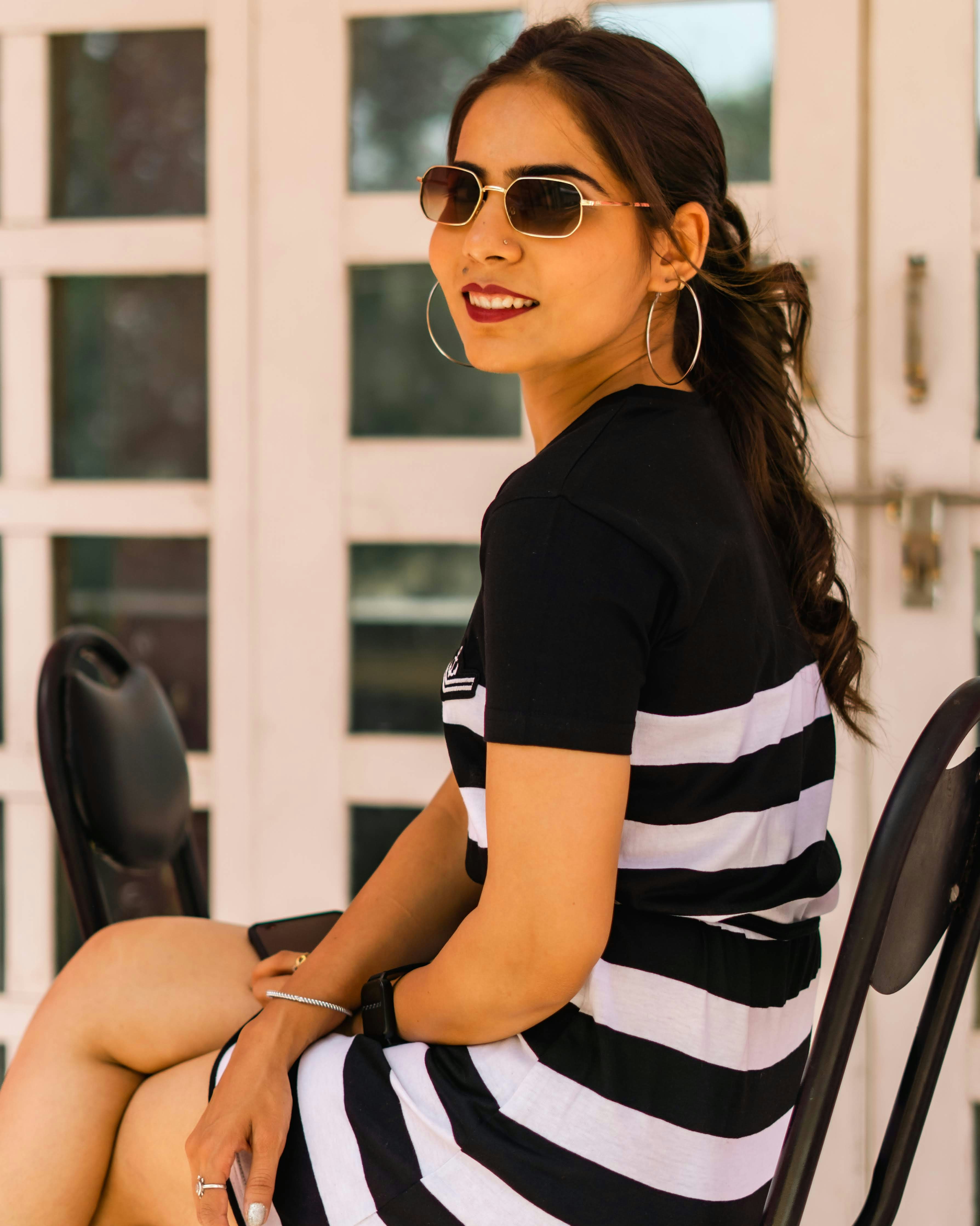 a woman in a black and white dress sitting on a chair