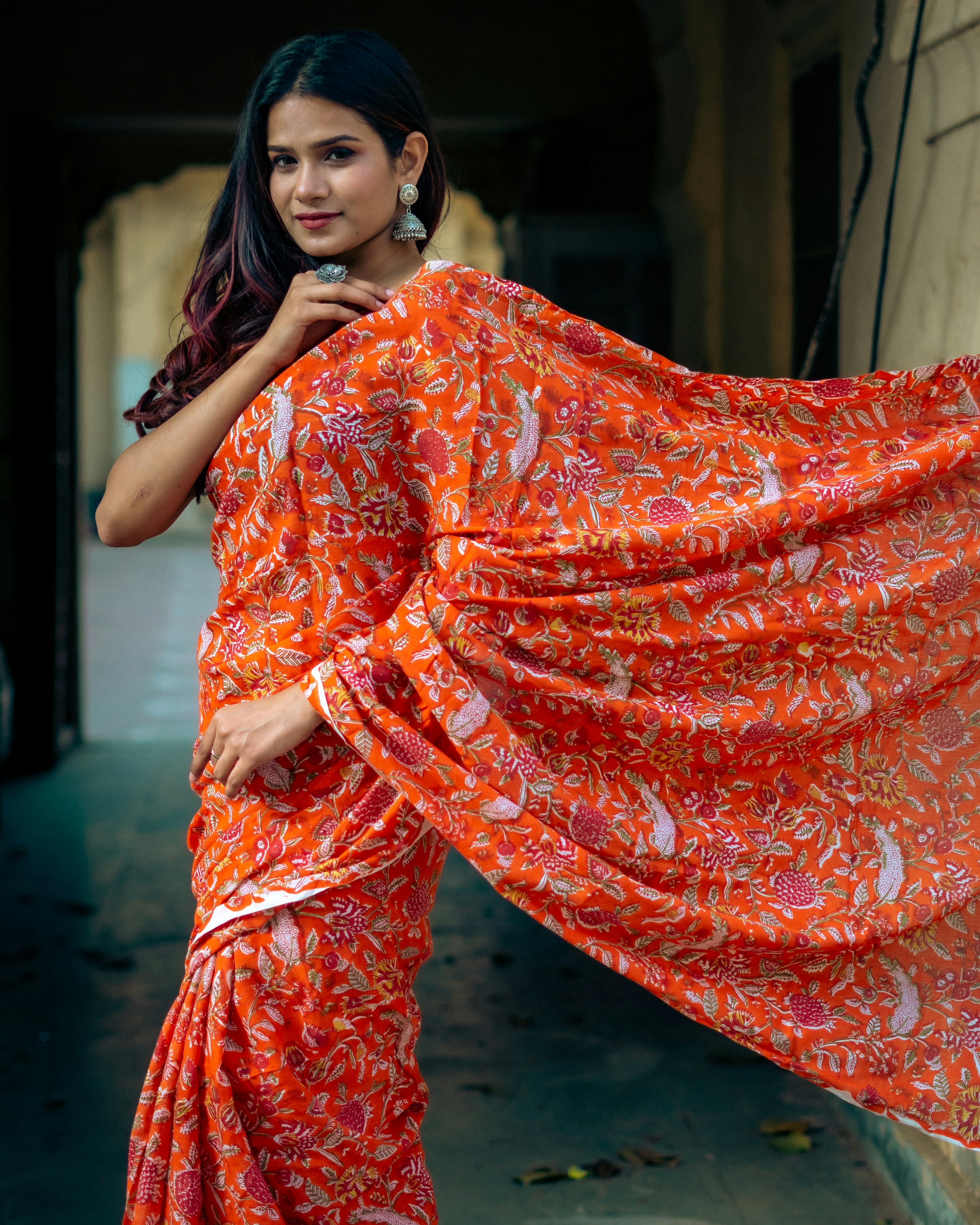 Woman in colorful bandhani print crop top, vibrant orange and pink tones, bright outdoor setting