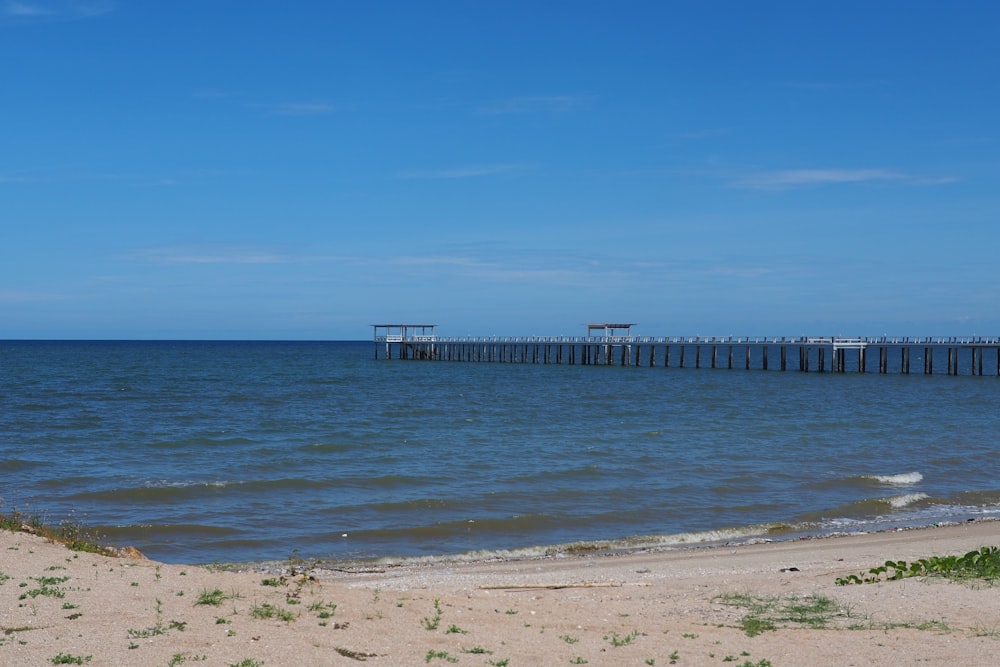 a beach with a pier in the distance