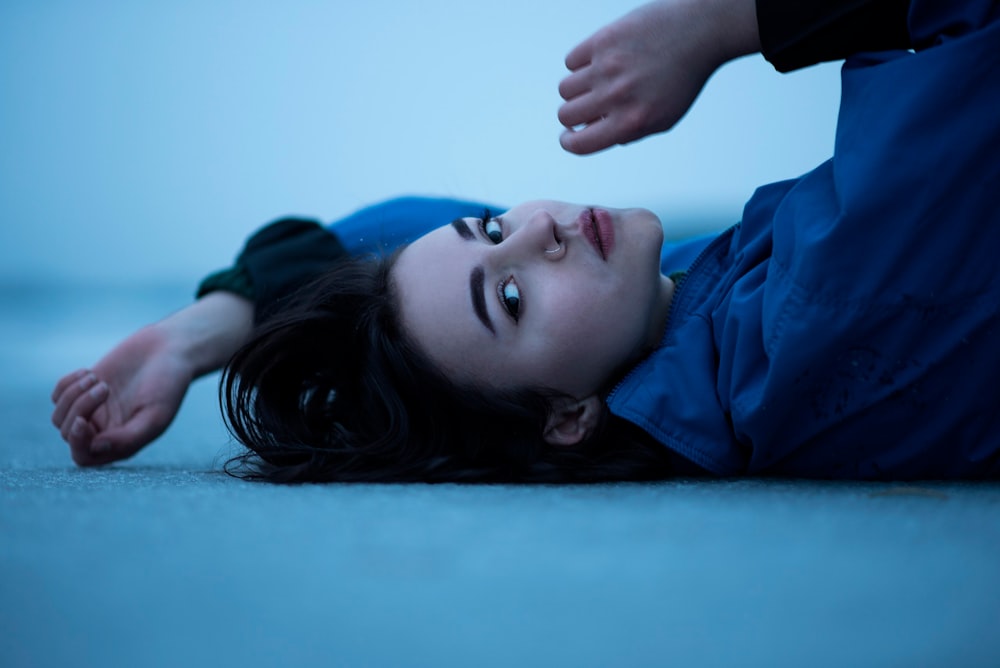a woman laying on the ground with her hand on her head