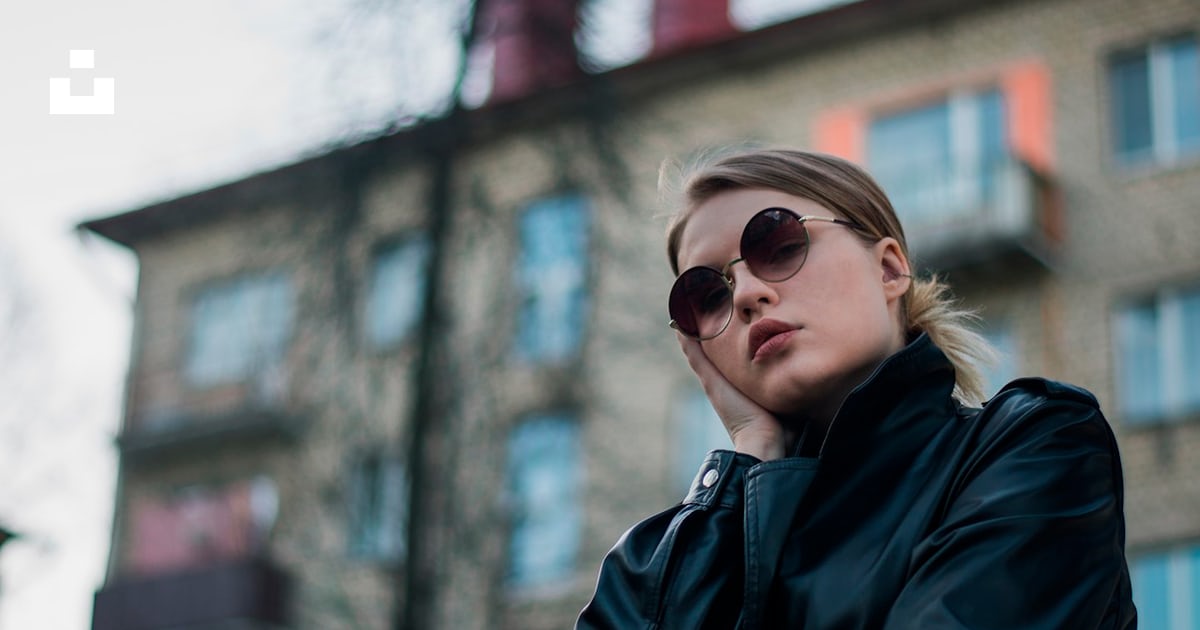 a woman in a black coat and sunglasses standing in front of a building ...