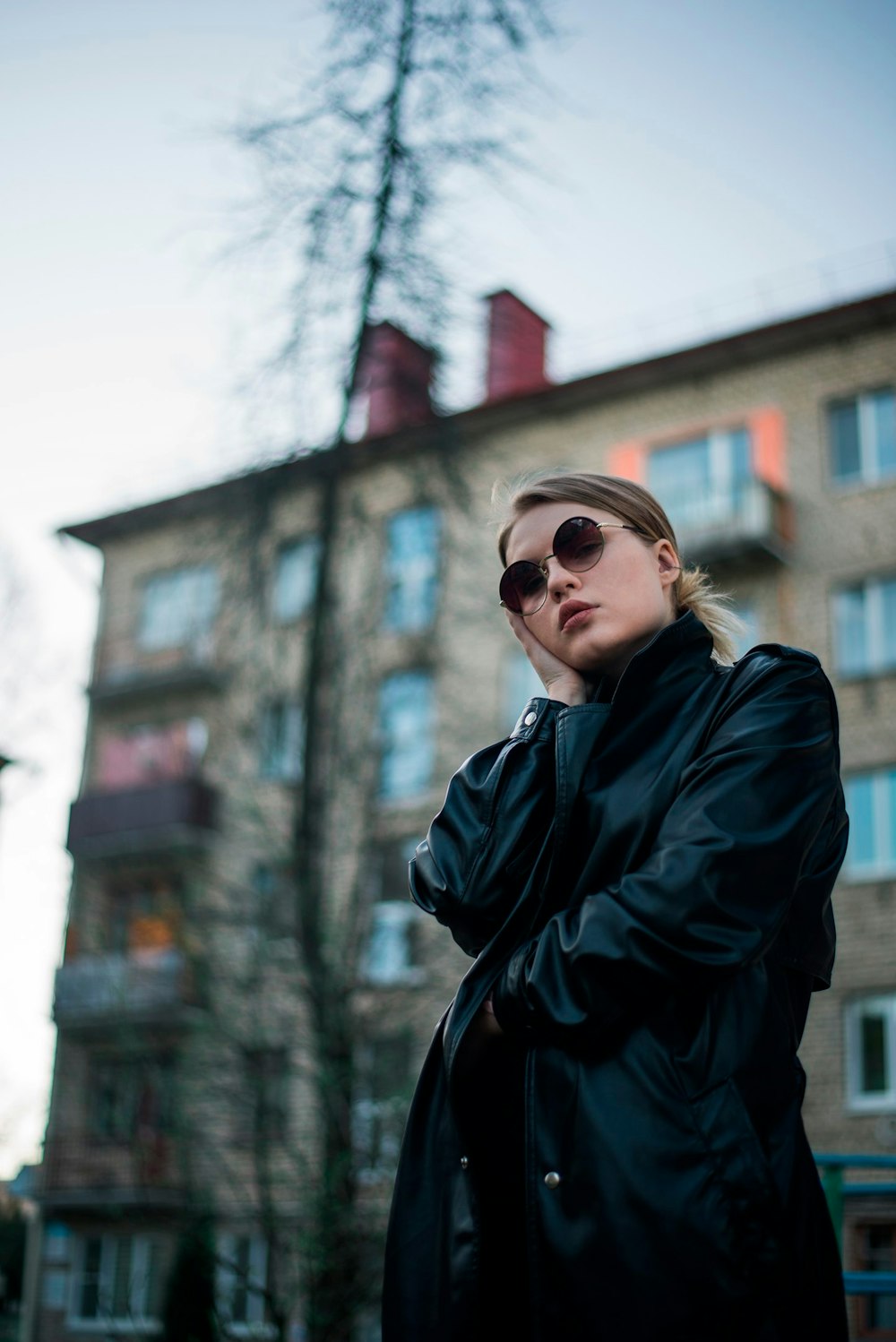 a woman in a black coat and sunglasses standing in front of a building