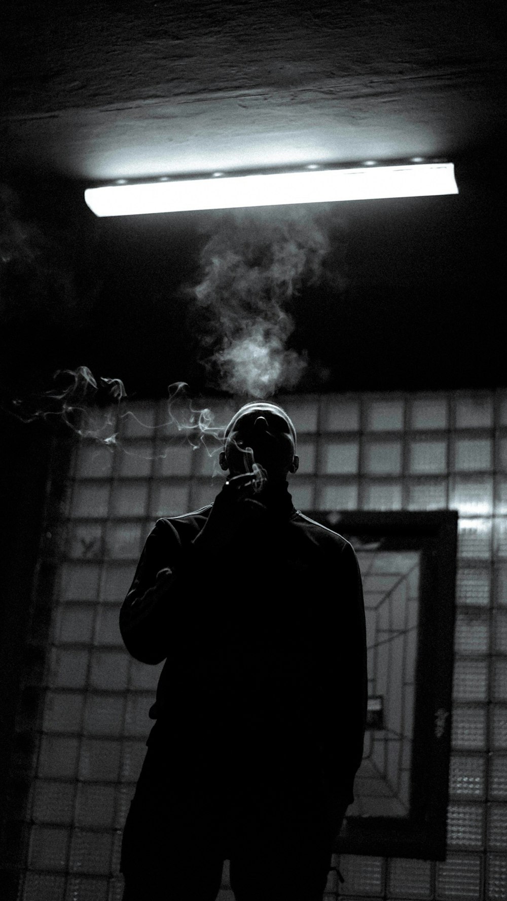 a man standing in a dark room with smoke coming out of his mouth