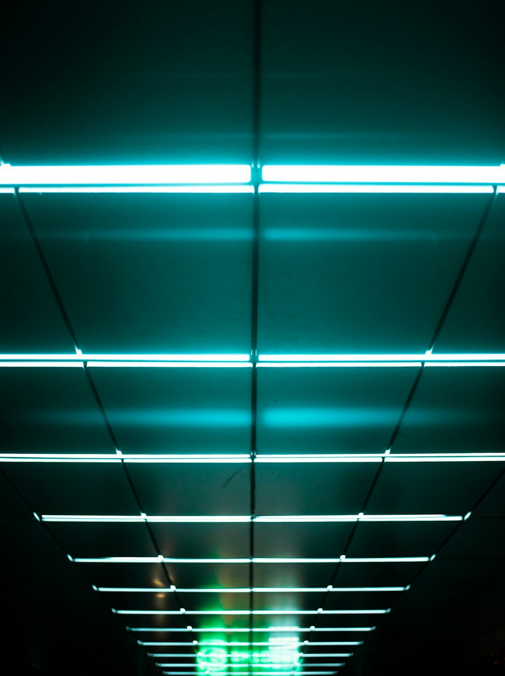 a long hallway with a green light above it