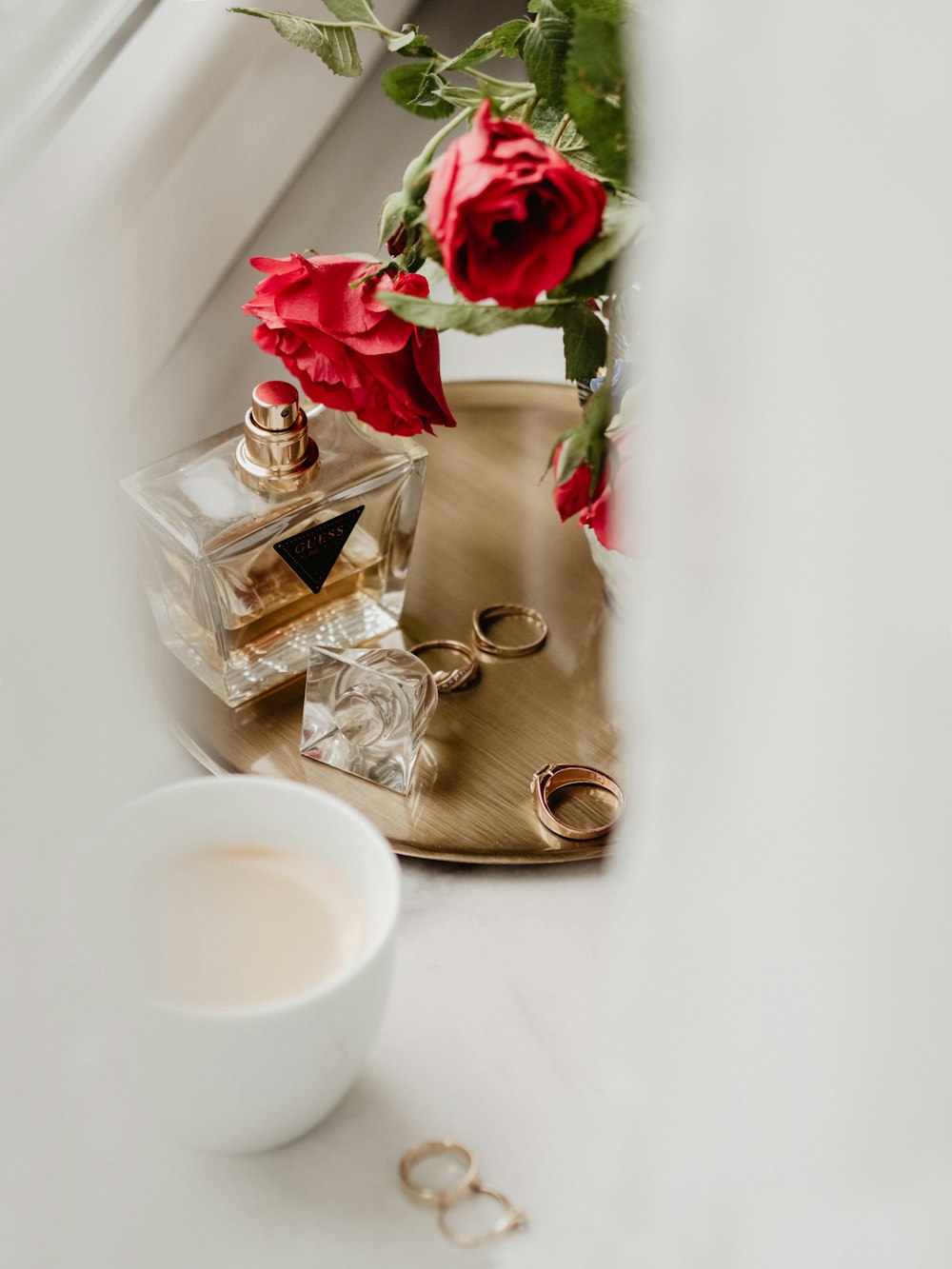 a cup of coffee sitting next to a vase of roses