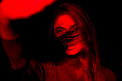 a woman with her face painted red in the dark