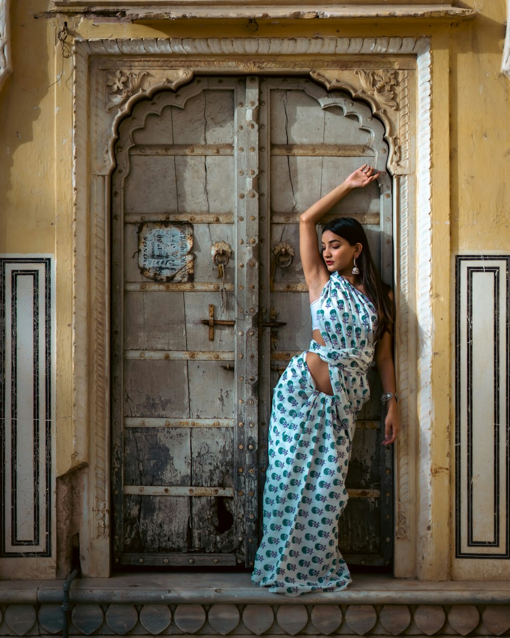 a woman in a blue and white sari standing in front of a door
