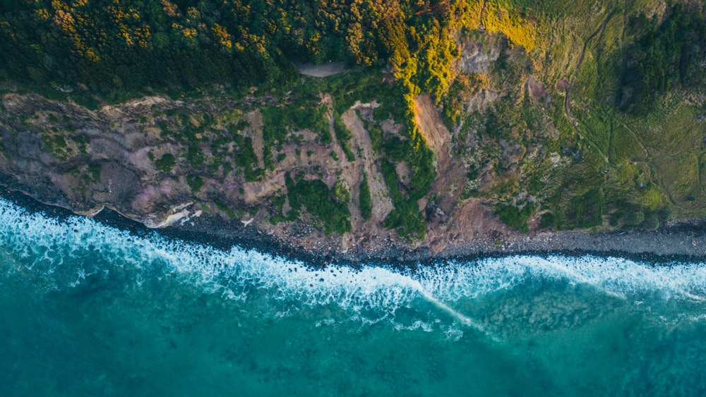 an aerial view of a body of water next to a lush green hillside