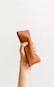 a hand holding a brown leather pouch