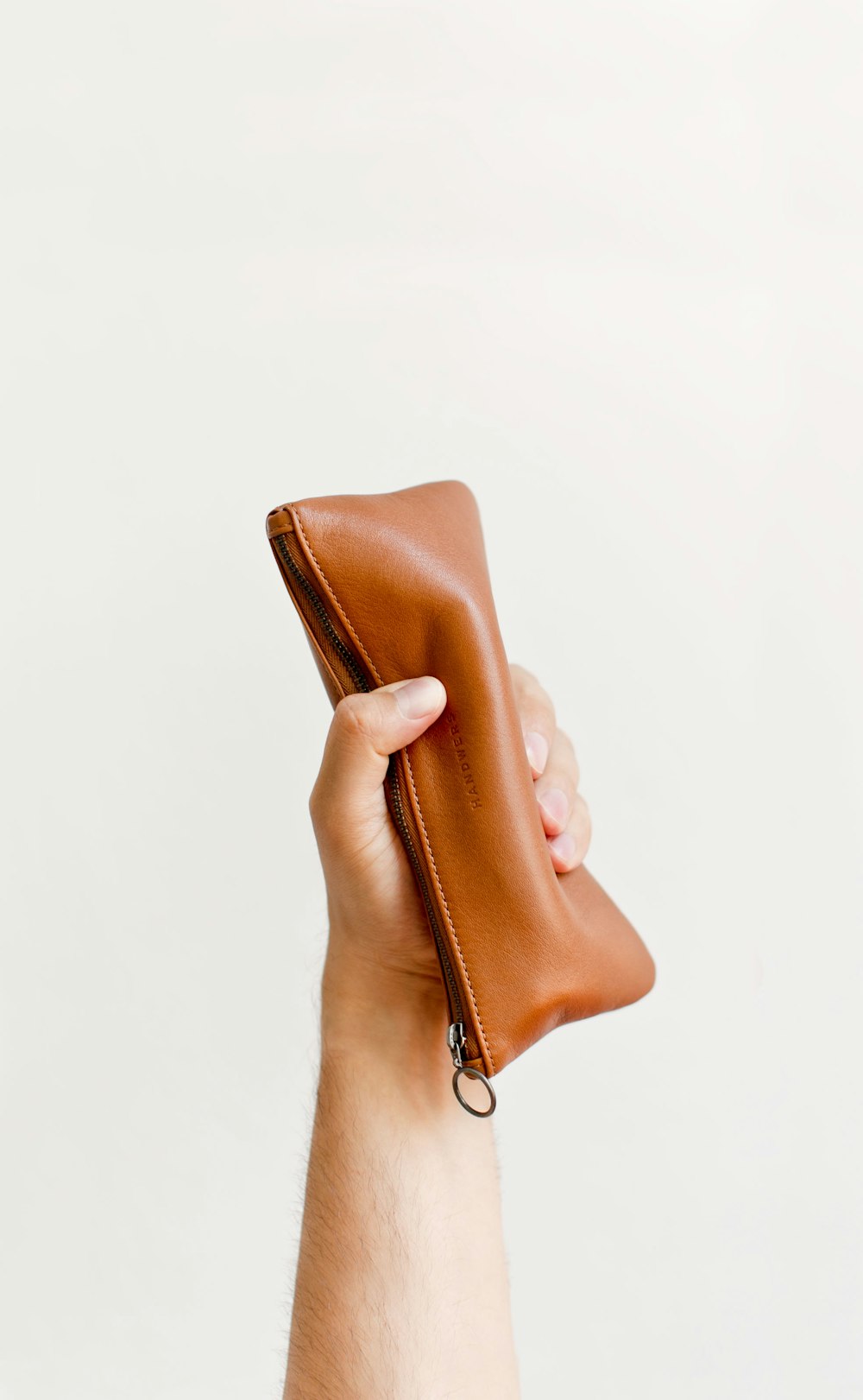 a hand holding a brown leather pouch