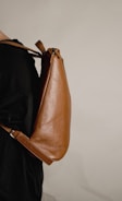 a woman is holding a brown leather bag