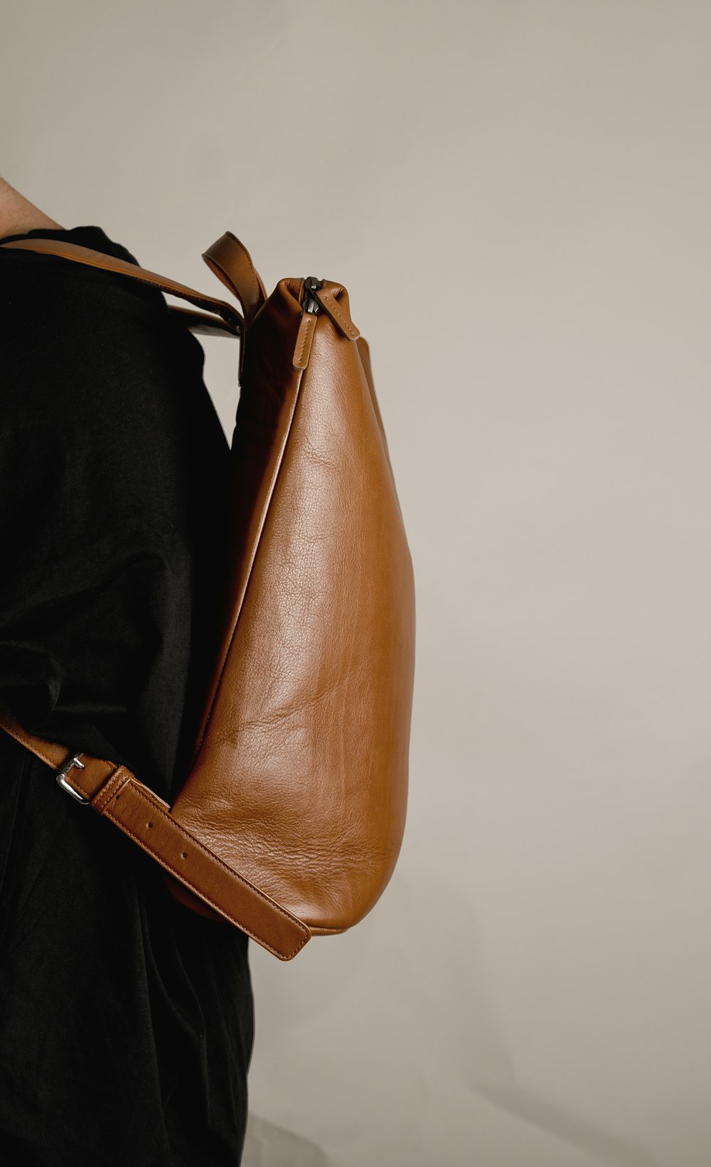 a woman is holding a brown leather bag