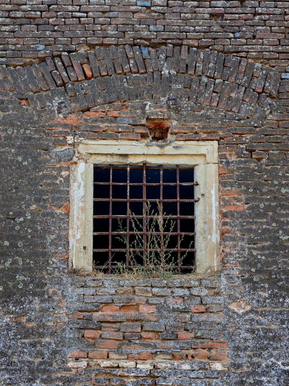 a brick wall with a window and bars on it