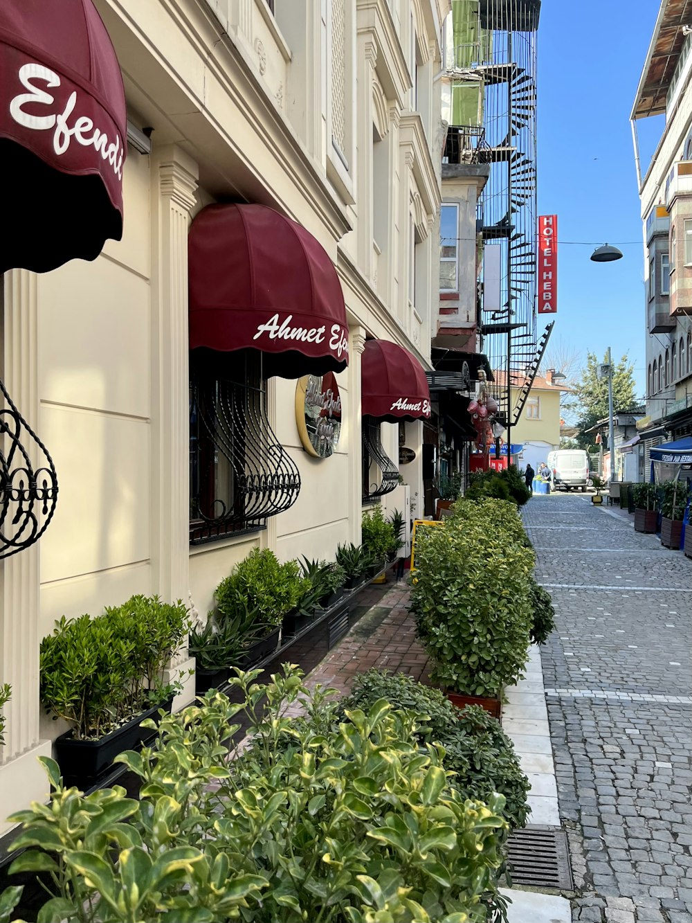 a street lined with potted plants next to a building