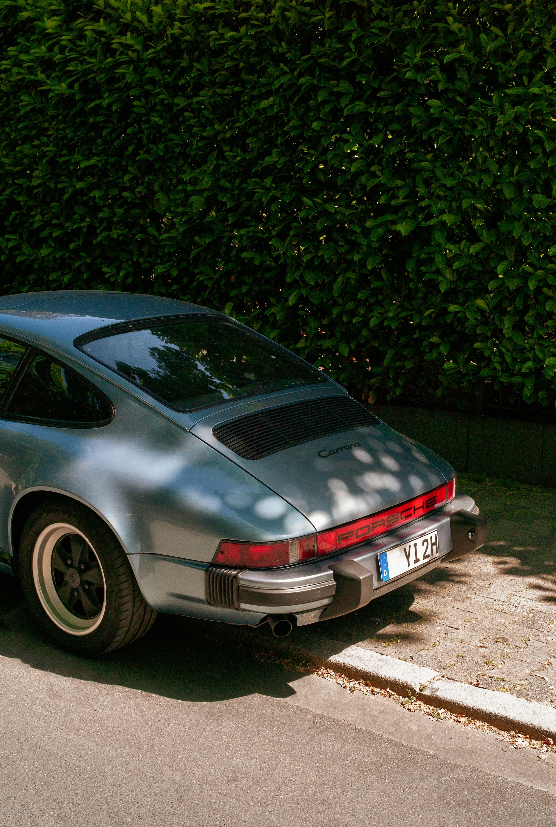 a silver porsche parked on the side of the road