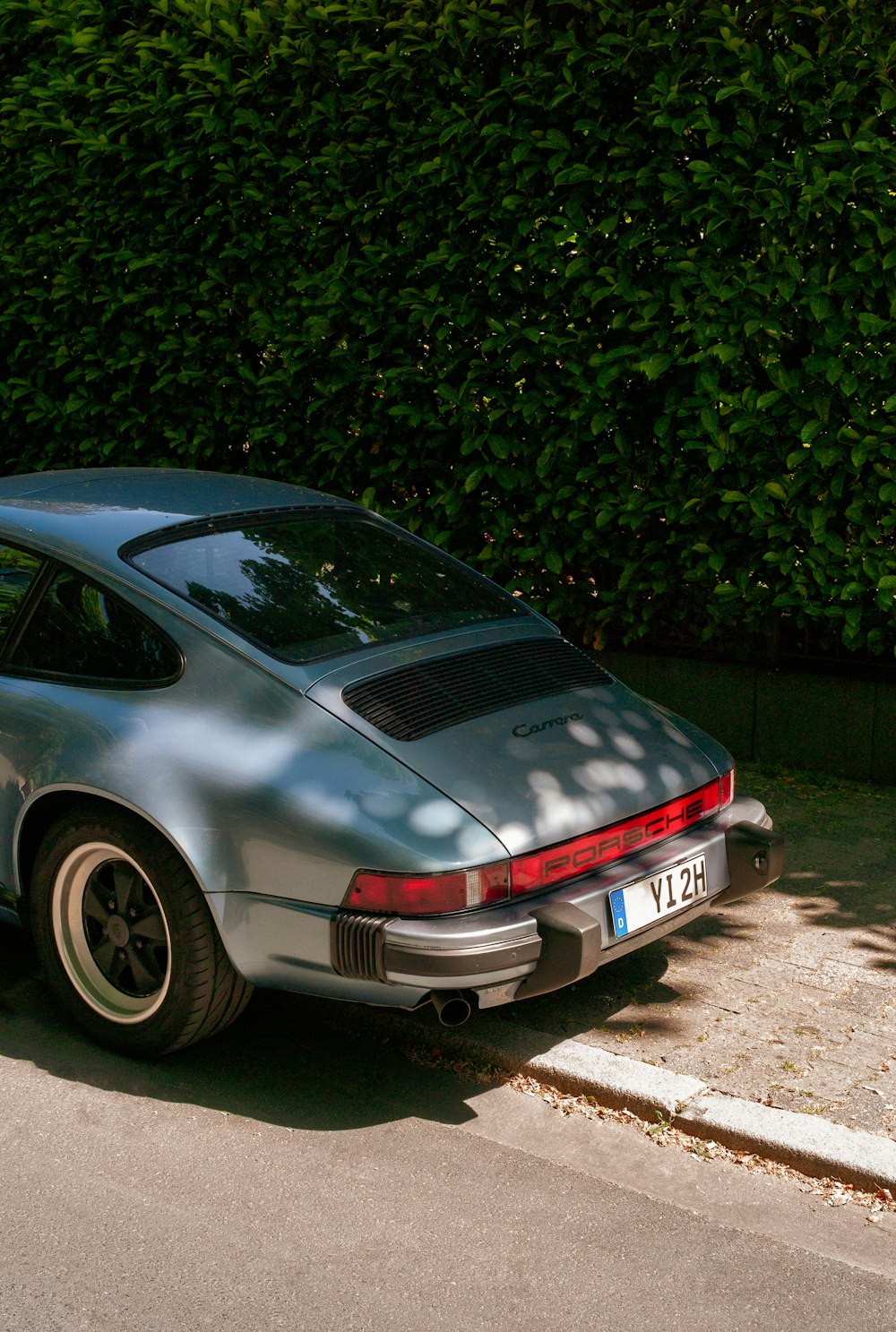 a silver porsche parked on the side of the road