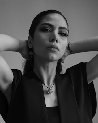 Artistic black-and-white photo of a woman in a structured blazer with bold accessories.