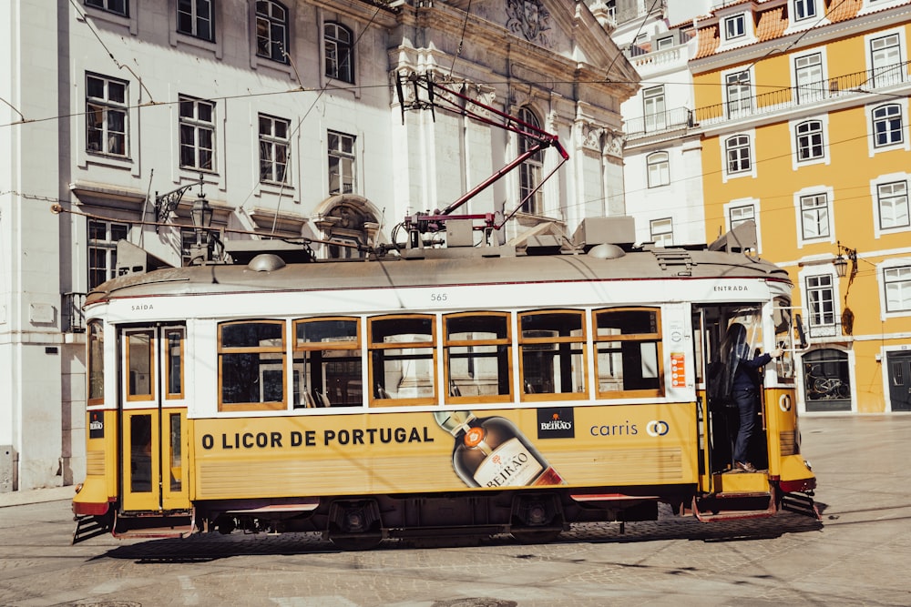 a yellow trolley car parked in front of a building