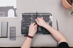 a man is working on a laptop with a screwdriver