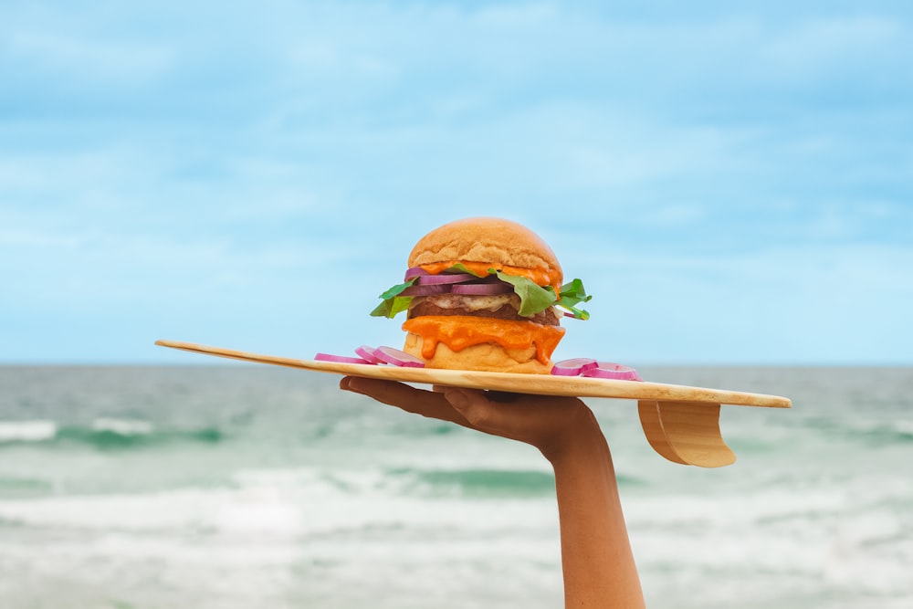 a person holding a plate with a hamburger on it