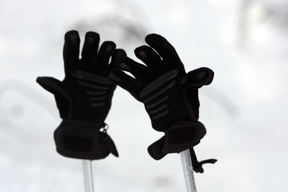 a pair of black gloves sitting on top of a pole