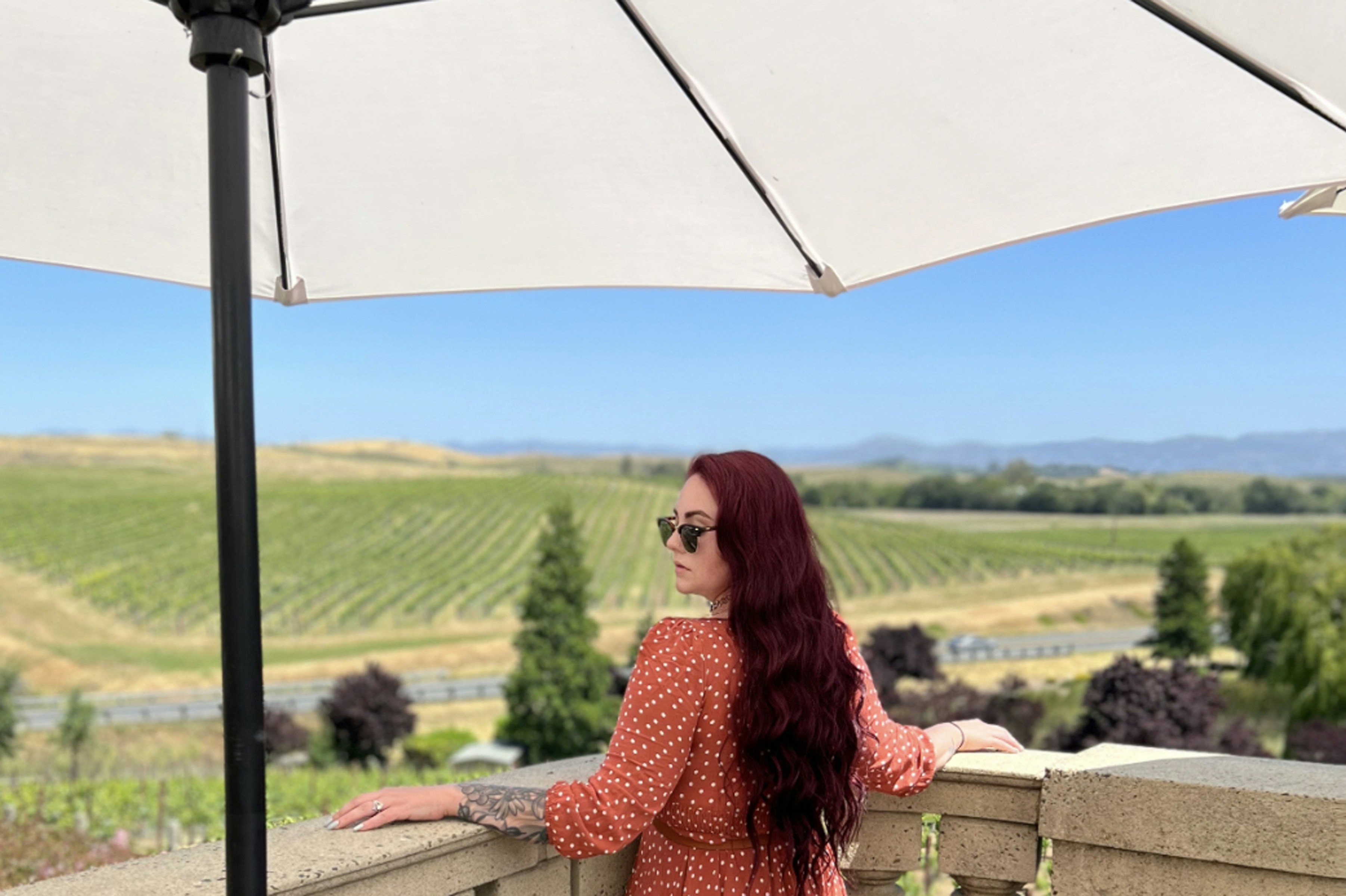 a woman standing on a balcony with an umbrella over her head