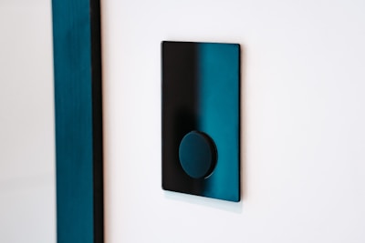 Close-up of a sleek, black smart switch panel glowing softly with neon blue accents on a modern wall.