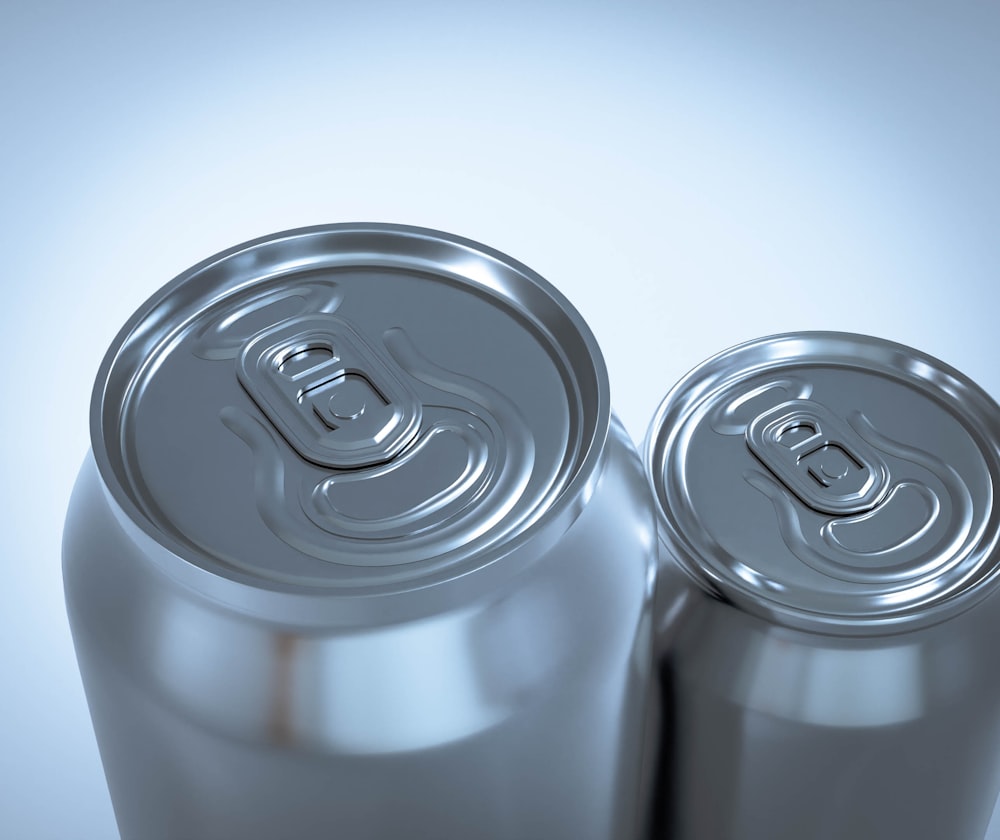 two silver soda cans sitting next to each other