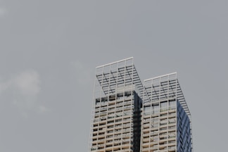 two tall buildings with balconies against a gray sky