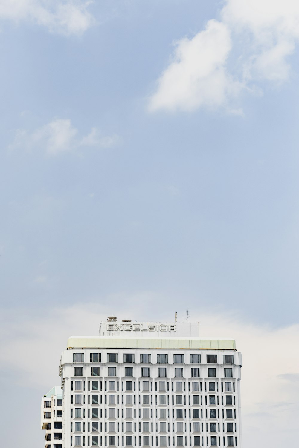 a tall white building sitting next to a lush green field