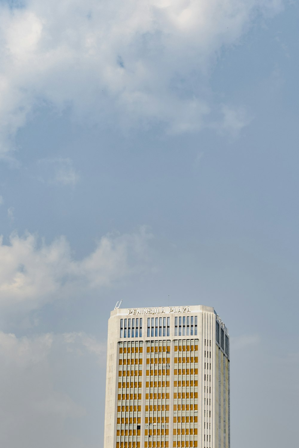 a plane flying in the sky over a tall building