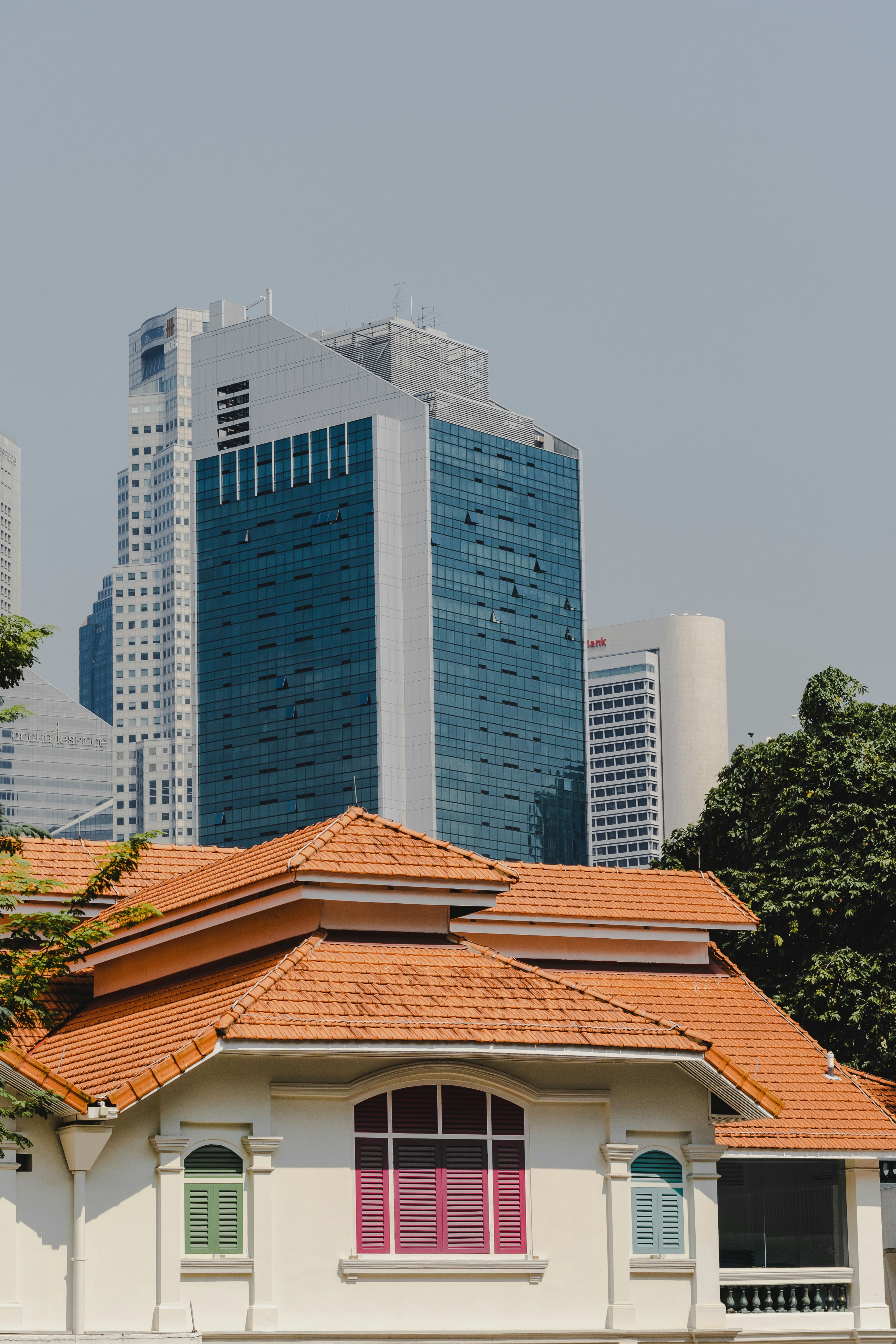 a white building with a red roof in front of tall buildings