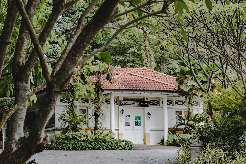 a white building with a red roof surrounded by trees