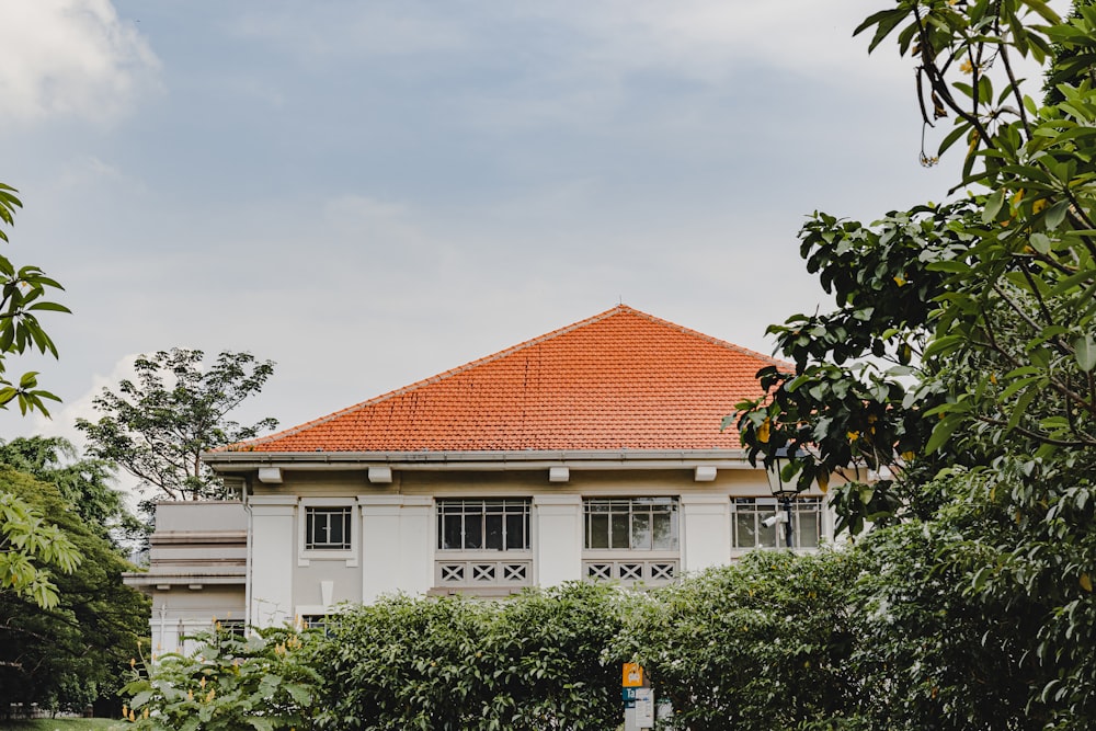 a white house with a red roof surrounded by trees