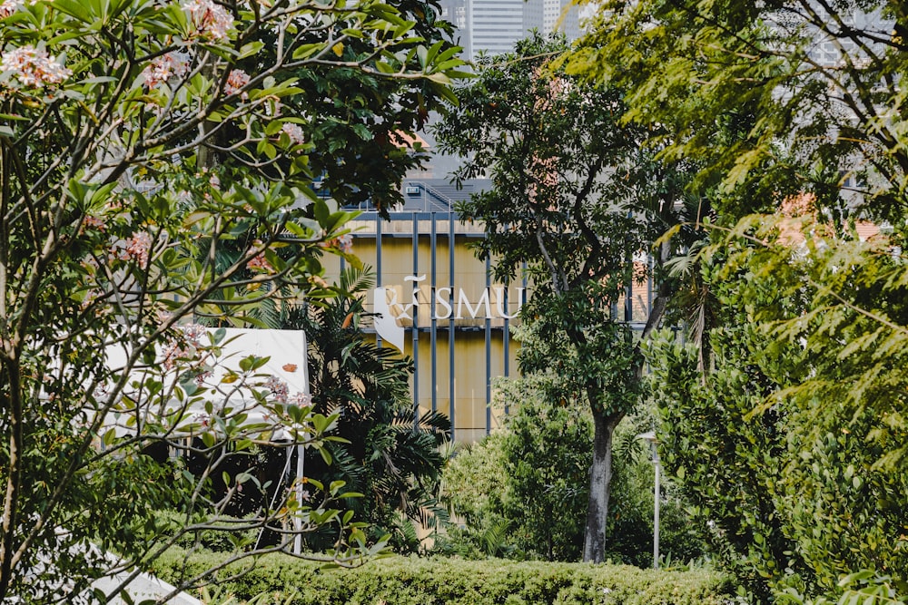 a yellow building surrounded by trees and bushes