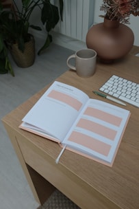 A cozy workspace with an open notebook, botanical illustrations, and a vintage pen.