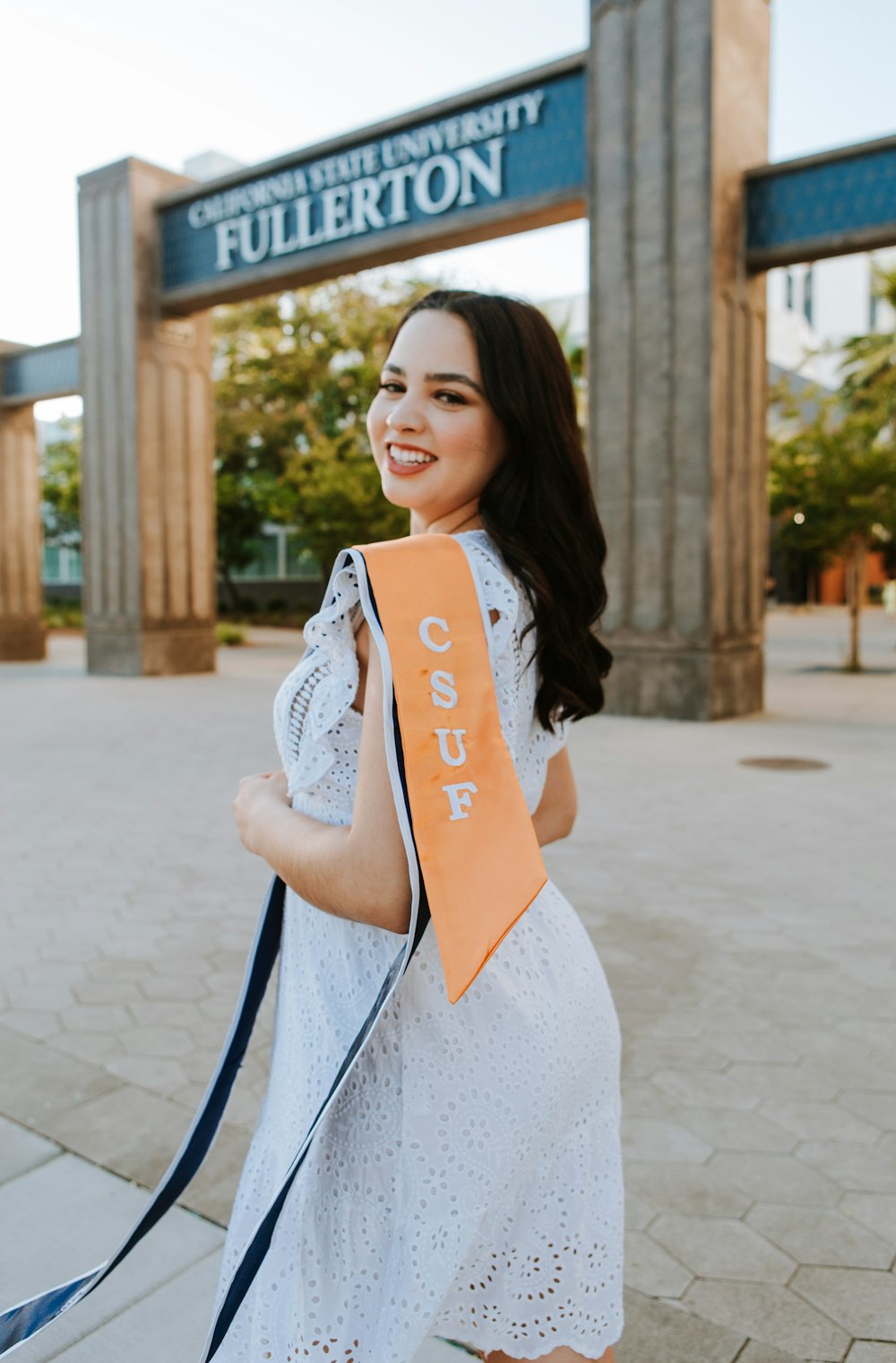 a woman in a white dress holding a orange sash