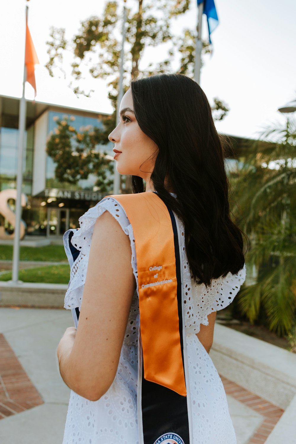 une femme en chemise blanche et écharpe noire et orange