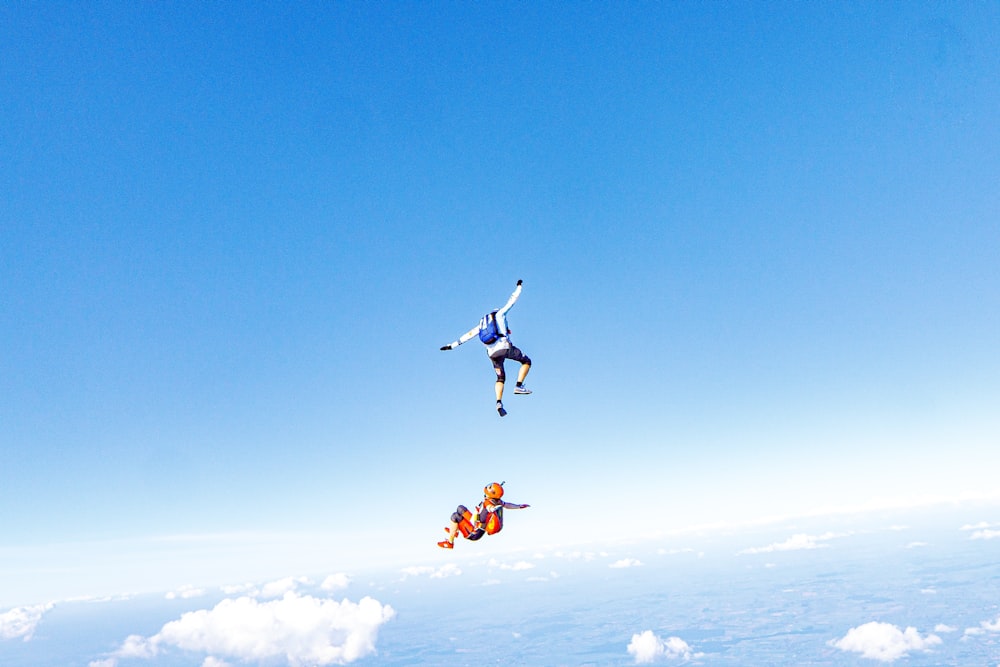 two people flying through the air on a pair of parachutes
