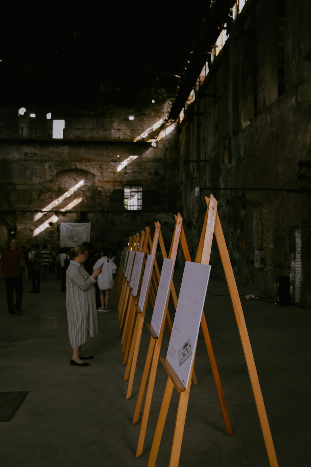 a group of people standing next to a row of easels