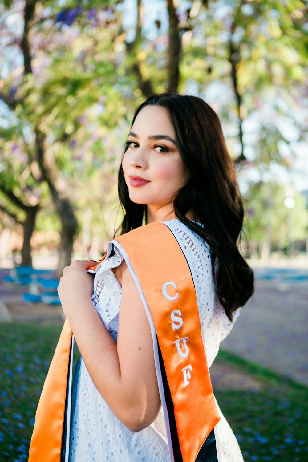 a woman in a white top and an orange sash