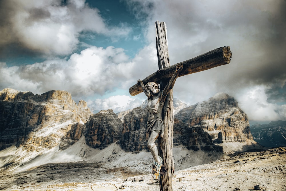 a wooden cross with a statue of a person on it