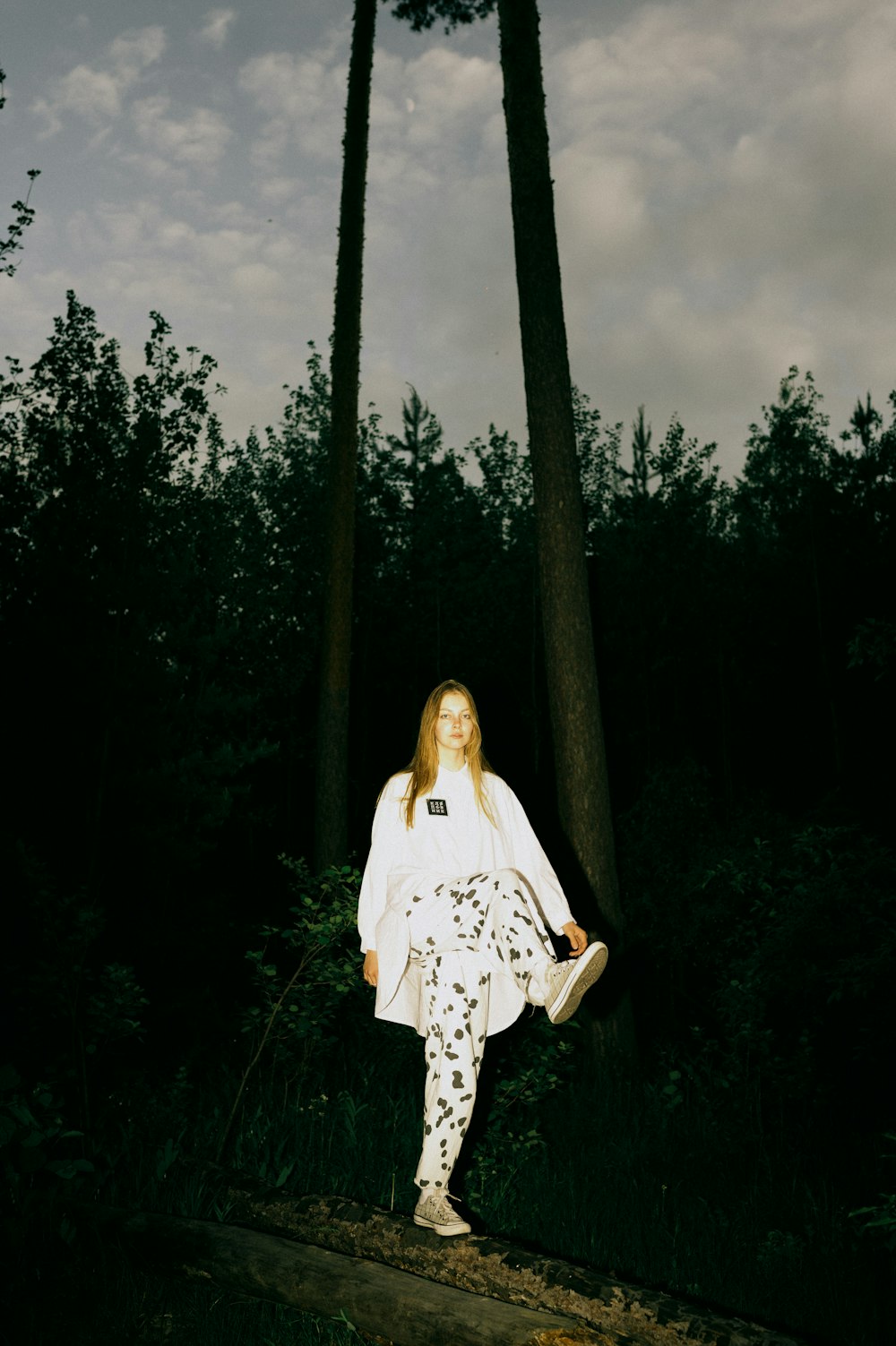 a woman in a white dress is standing in the woods