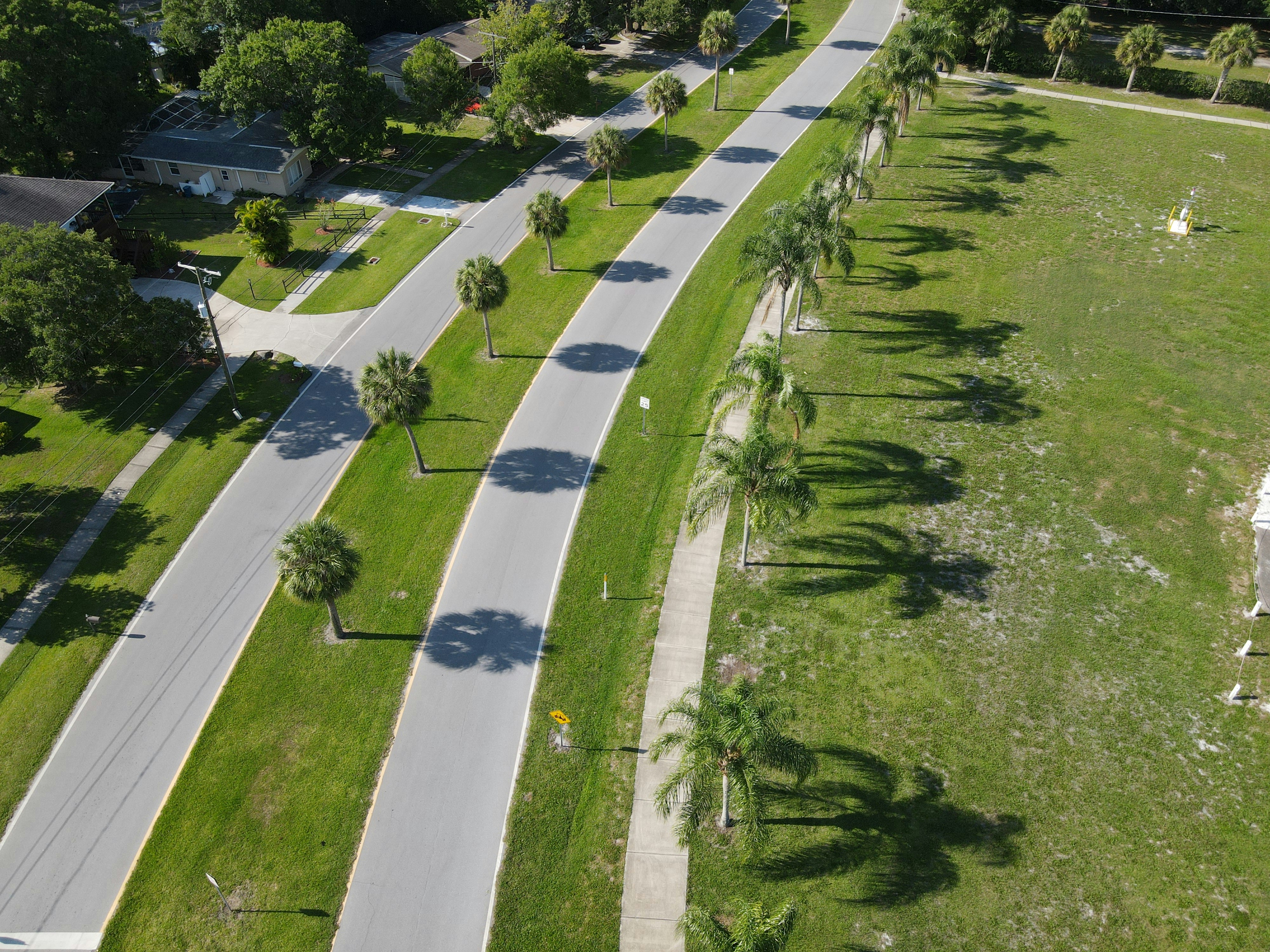 Aerial view of Florida residential neighborhood with tree-lined streets, warm afternoon light, well-maintained properties