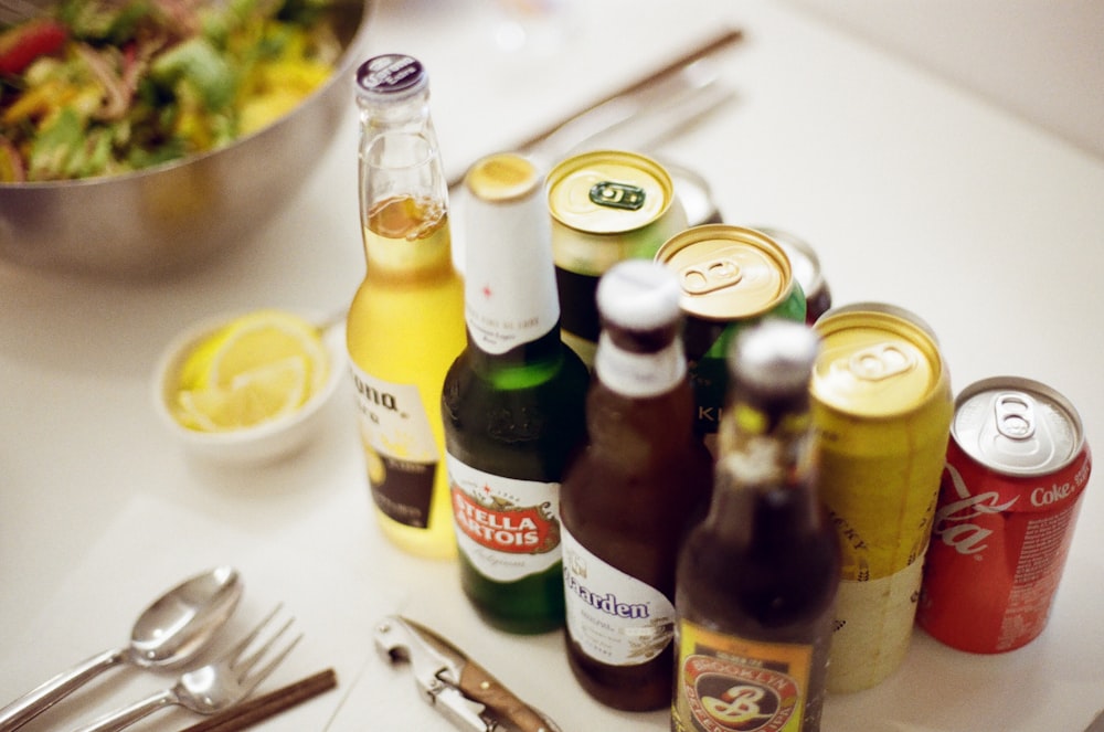 una mesa cubierta con botellas de cerveza y un tazón de ensalada