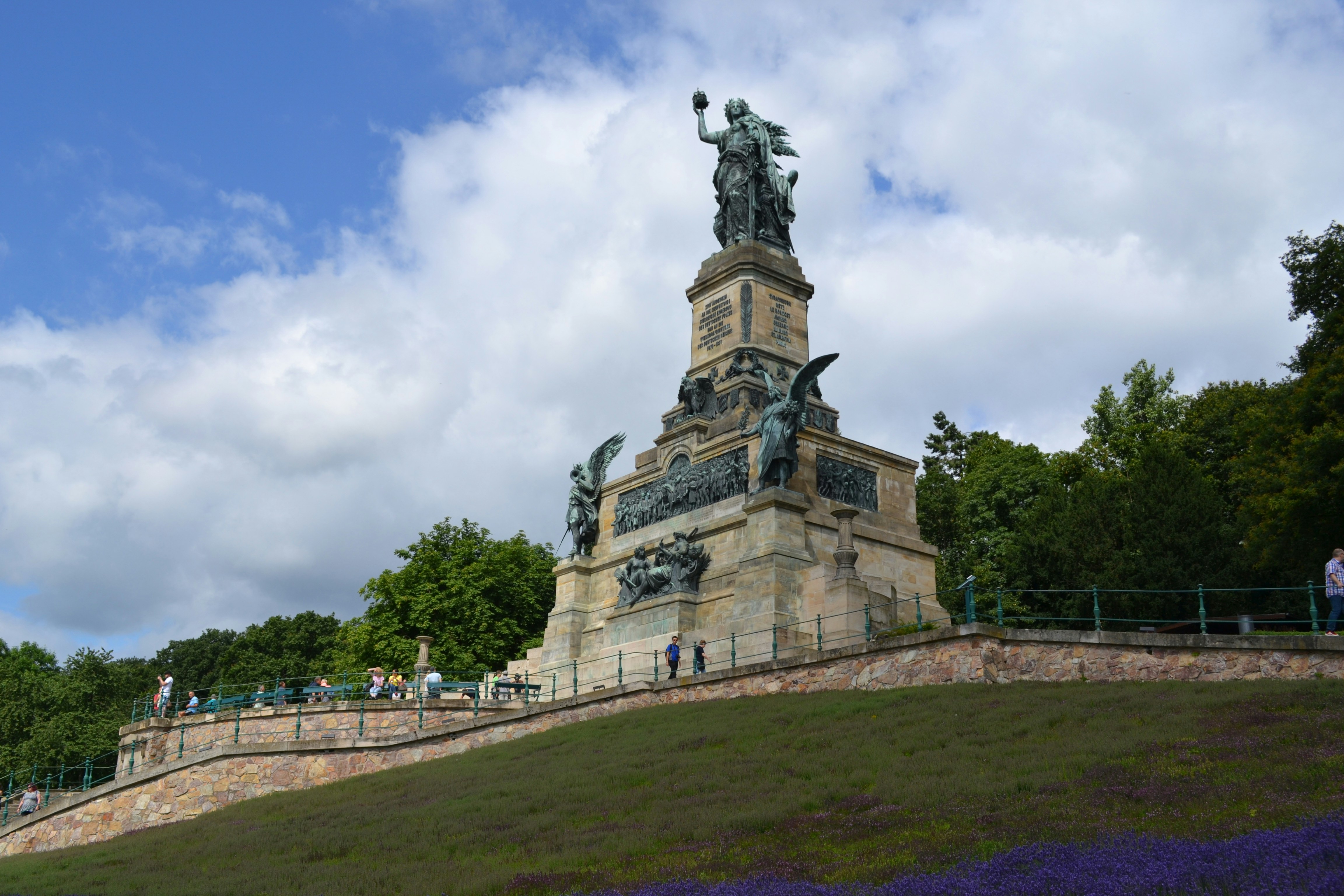 a statue on top of a hill surrounded by purple flowers