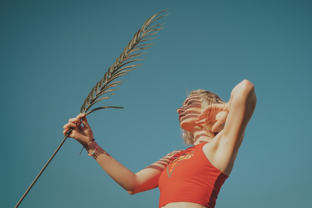 a woman in a bikini holding a palm tree