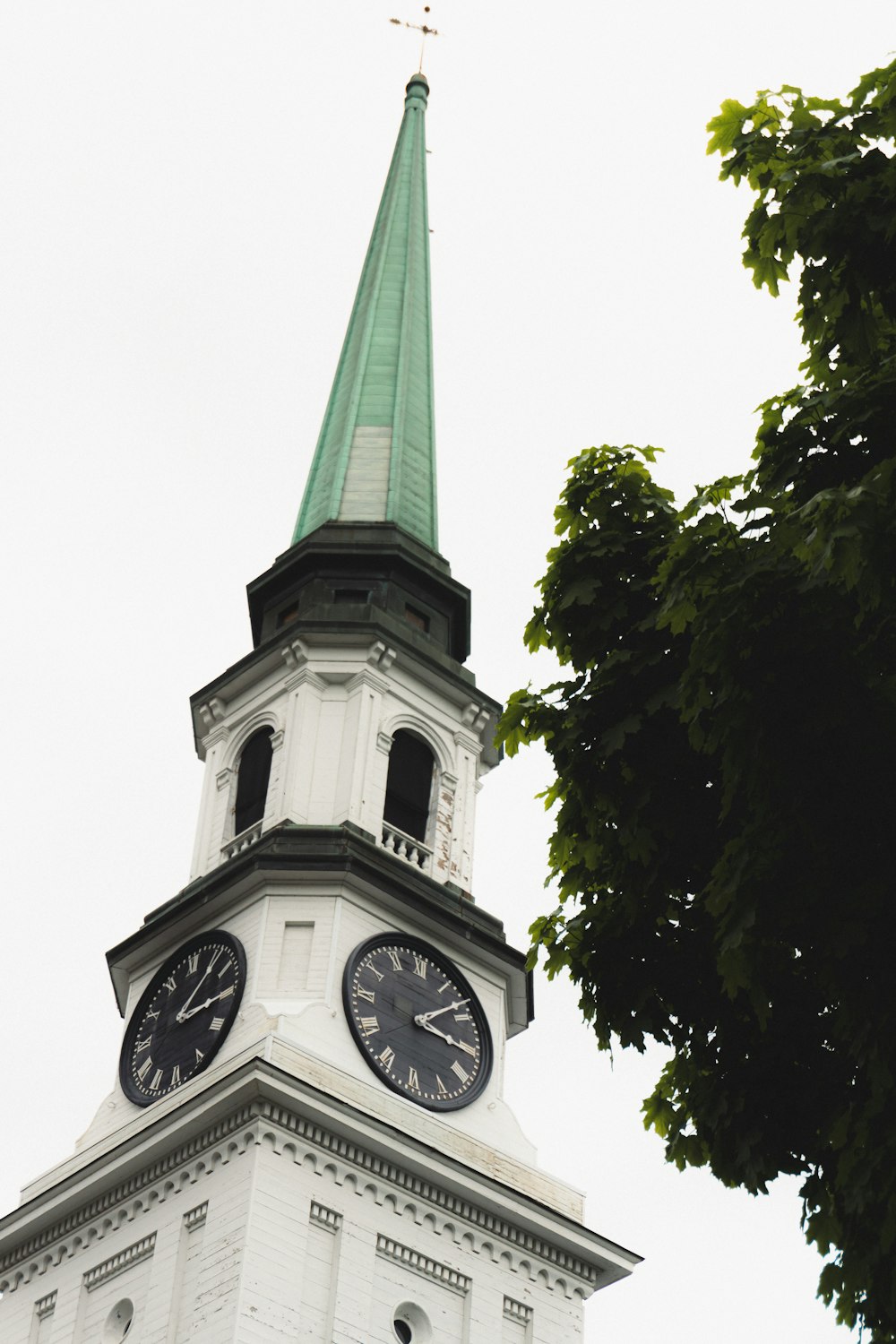 a white clock tower with a green steeple