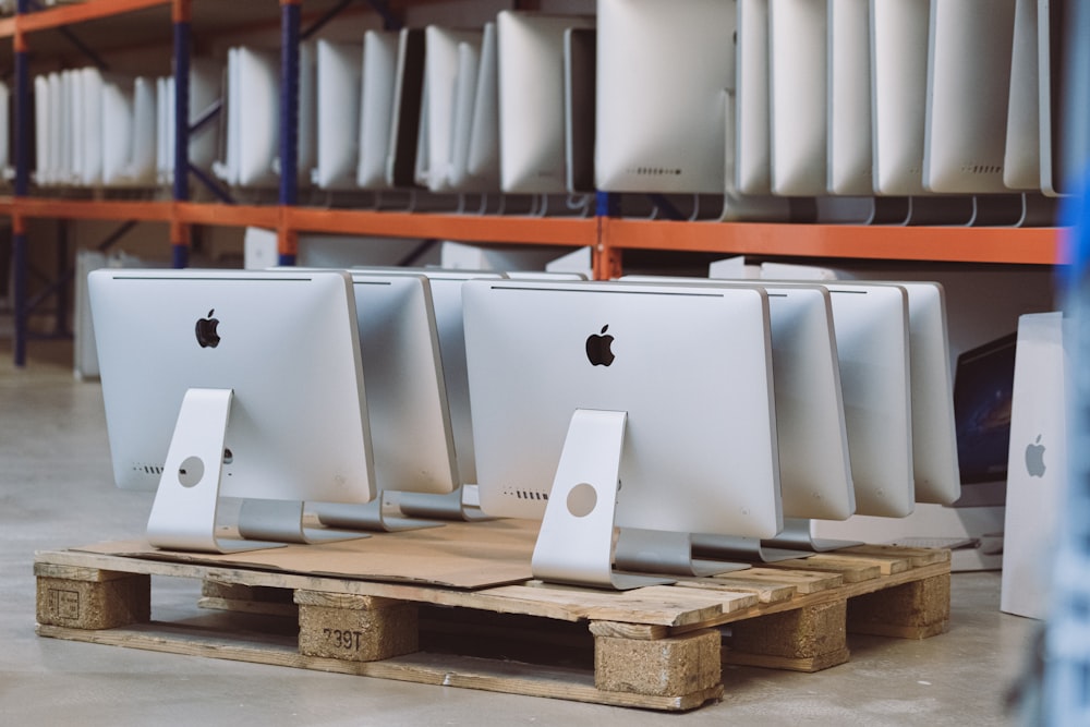 Una fila de computadoras Apple sentadas en paletas en una tienda