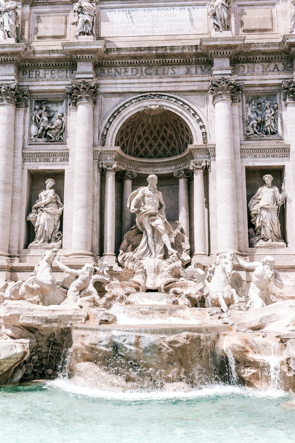 a fountain with statues and a clock on the side of it